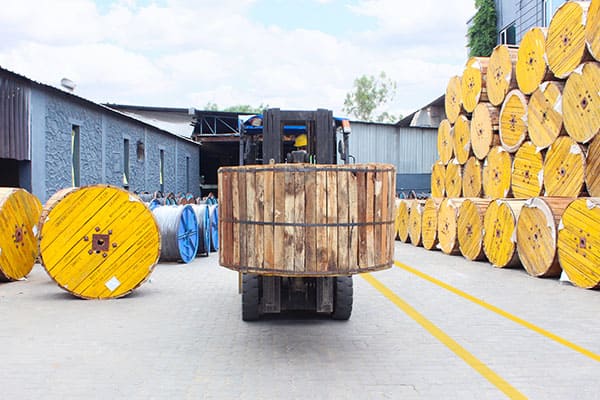 Forklift lifting a large reel of wire in a warehouse