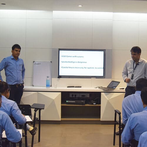 Two people giving a lecture to students in a room 