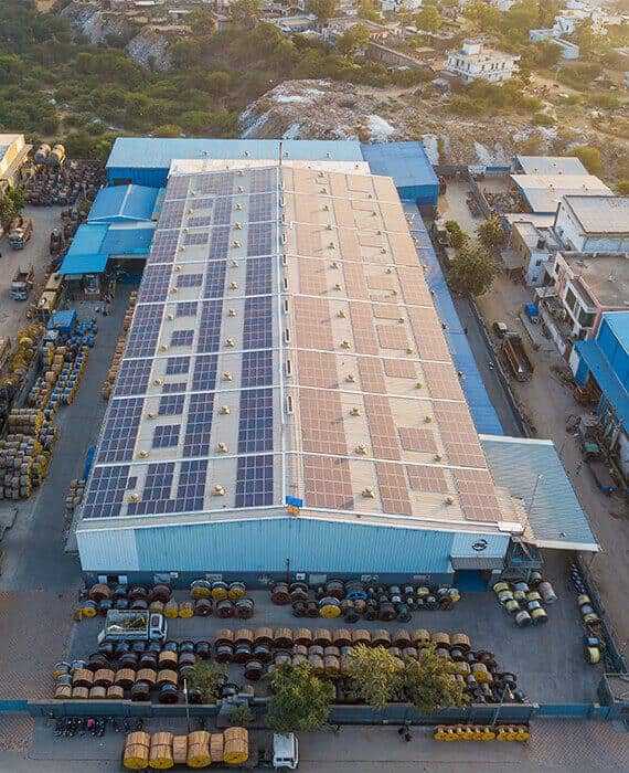 An aerial shot of a factory and wire warehouse covered with solar panels