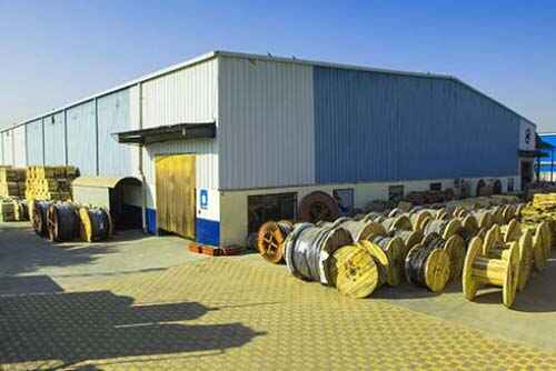 A large warehouse with many rolls of wire in front of it.